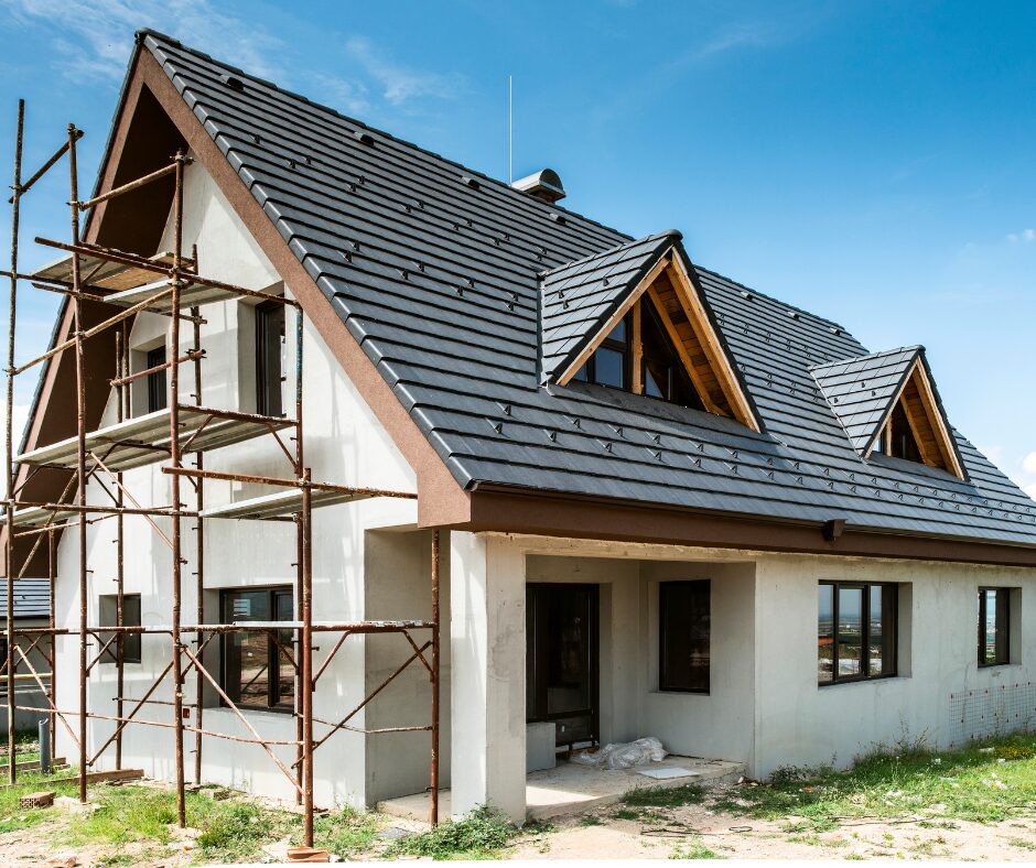 Dom w trackie budowy. Po lewej stronie domu stoi rusztowanie.
