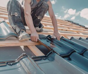 Pracownik montuje dachówki na dachu budynku